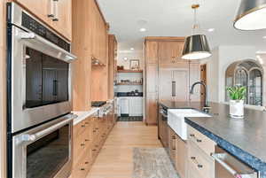 Kitchen featuring appliances with stainless steel finishes, light brown cabinetry, light wood-style floors, pendant lighting, and recessed lighting