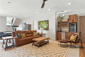 Living room with light wood finished floors, recessed lighting, wine cooler, a ceiling fan, and stairs