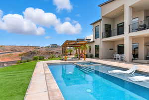 View of swimming pool with a patio area, a pool with connected hot tub, a yard, and a pergola