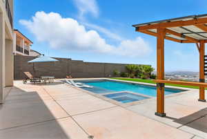 View of pool with a patio area, a pool with connected hot tub, and a fenced backyard