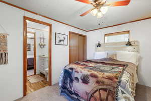 Bedroom featuring a textured ceiling, wood finished floors, connected bathroom, crown molding, and a ceiling fan