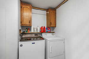 Washroom featuring a textured ceiling, cabinet space, and separate washer and dryer
