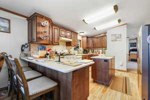 Kitchen featuring tasteful backsplash, light wood-style flooring, a textured ceiling, light countertops, and a center island