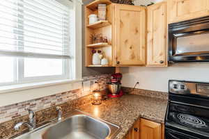 Kitchen with open shelves, black appliances, decorative backsplash, and light brown cabinets