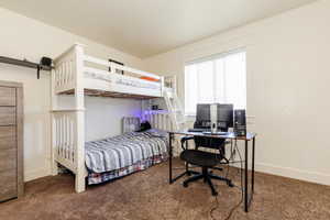 Carpeted bedroom featuring a barn door and a desk