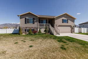Single story home with an attached garage, driveway, stone siding, covered porch, and stairs