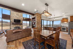 Dining room featuring healthy amount of natural light, light wood-style floors, a stone fireplace, a textured ceiling, and recessed lighting