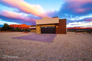 View of front of home featuring driveway, a mountain view, stone siding, and stucco siding
