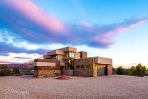 Modern home featuring stone siding, stucco siding, an attached garage, and driveway