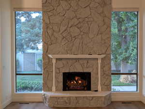 Unfurnished living room with a stone fireplace and wood finished floors