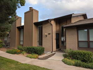 View of front of property featuring a chimney and brick siding