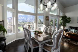 Dining room with dark wood-style flooring, a mountain view, and a towering ceiling