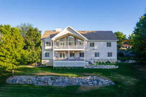 Rear view of property with a lawn, a chimney, stairway, and a balcony