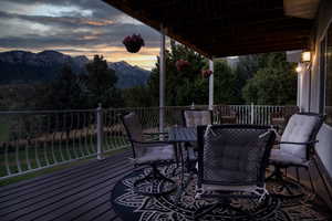 Deck at dusk with a mountain view and outdoor dining space