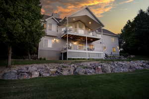 Back of house at dusk with a lawn, two decks a chimney, and stucco siding