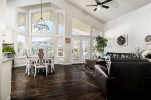 Living room featuring high vaulted ceiling, dark wood finished floors, healthy amount of natural light, a ceiling fan, and a chandelier
