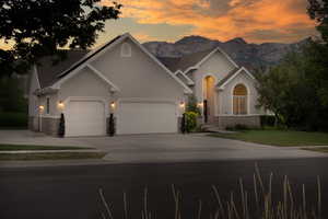 View of front of house featuring a garage, stucco siding, driveway, a mountain view, and stone siding