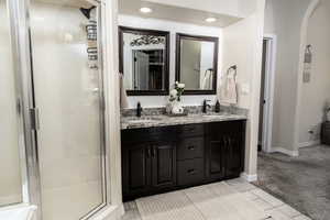 Primary bathroom featuring a shower stall, light tile patterned floors, and double vanity