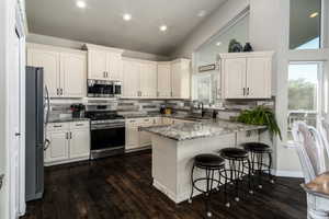 Kitchen with dark stone counters, decorative backsplash, appliances with stainless steel finishes, recessed lighting, and a peninsula