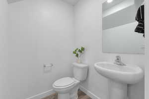 Half bath with baseboards and wood finished floors