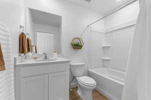 Full bath featuring shower / bath combination with curtain, light wood-type flooring, and vanity