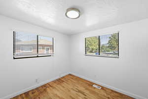 Unfurnished room featuring a textured ceiling, light wood-type flooring, and plenty of natural light