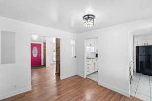 Unfurnished dining area featuring light wood-type flooring and baseboards