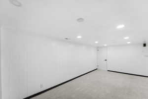 Finished below grade area with recessed lighting, light carpet, and wooden walls
