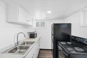 Kitchen featuring black appliances, white cabinets, dark wood-style flooring, and light countertops