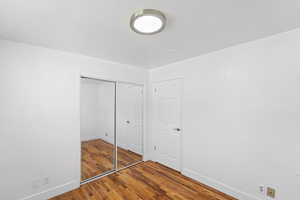 Unfurnished bedroom featuring wood finished floors and a closet