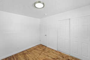 Unfurnished bedroom with light wood-style flooring, a textured ceiling, and a closet