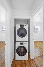 Laundry room with wood finished floors and stacked washer / drying machine