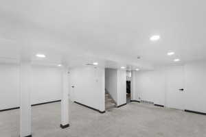 Finished below grade area with light colored carpet, stairs, recessed lighting, and wooden walls