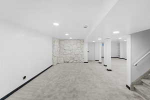 Finished basement featuring light carpet, stairway, and recessed lighting