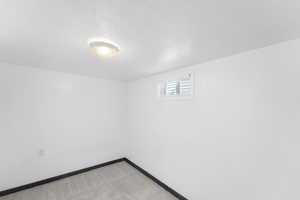 Below grade area featuring light carpet and a textured ceiling