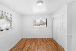 Unfurnished bedroom with wood finished floors and a closet