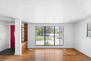 Unfurnished living room featuring light wood-type flooring and baseboards