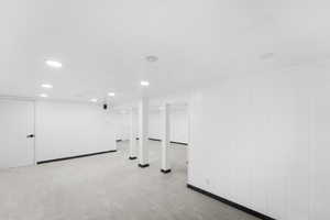 Finished below grade area with light colored carpet, recessed lighting, and wood walls