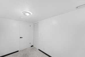 Carpeted empty room with a textured ceiling and baseboards