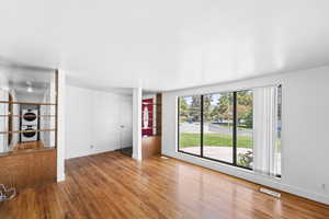 Unfurnished living room with light wood-type flooring and estacked washer and dryer