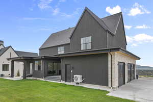 Back of property with stone siding, a patio area, stucco siding, and a yard