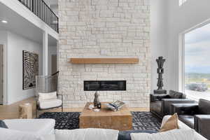 Living area featuring a stone fireplace, a high ceiling, and wood finished floors