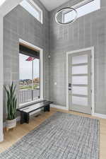 Foyer entrance featuring a high ceiling, light wood-type flooring, and tile walls