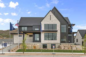 View of front of house with stone siding and a shingled roof