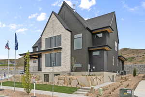 View of side of property with stone siding and a shingled roof