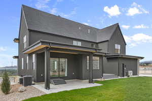 Back of property featuring a patio, a lawn, and a shingled roof