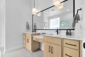 Bathroom featuring double vanity, light tile patterned flooring, and a tile shower