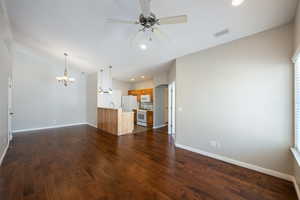 Unfurnished living room featuring recessed lighting, a ceiling fan, dark wood-type flooring, a chandelier, and lofted ceiling