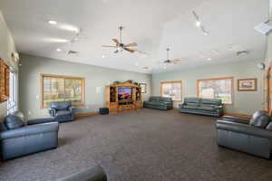 Carpeted living room featuring track lighting, ceiling fan, recessed lighting, and lofted ceiling