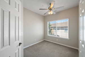 Empty room featuring carpet floors and a ceiling fan